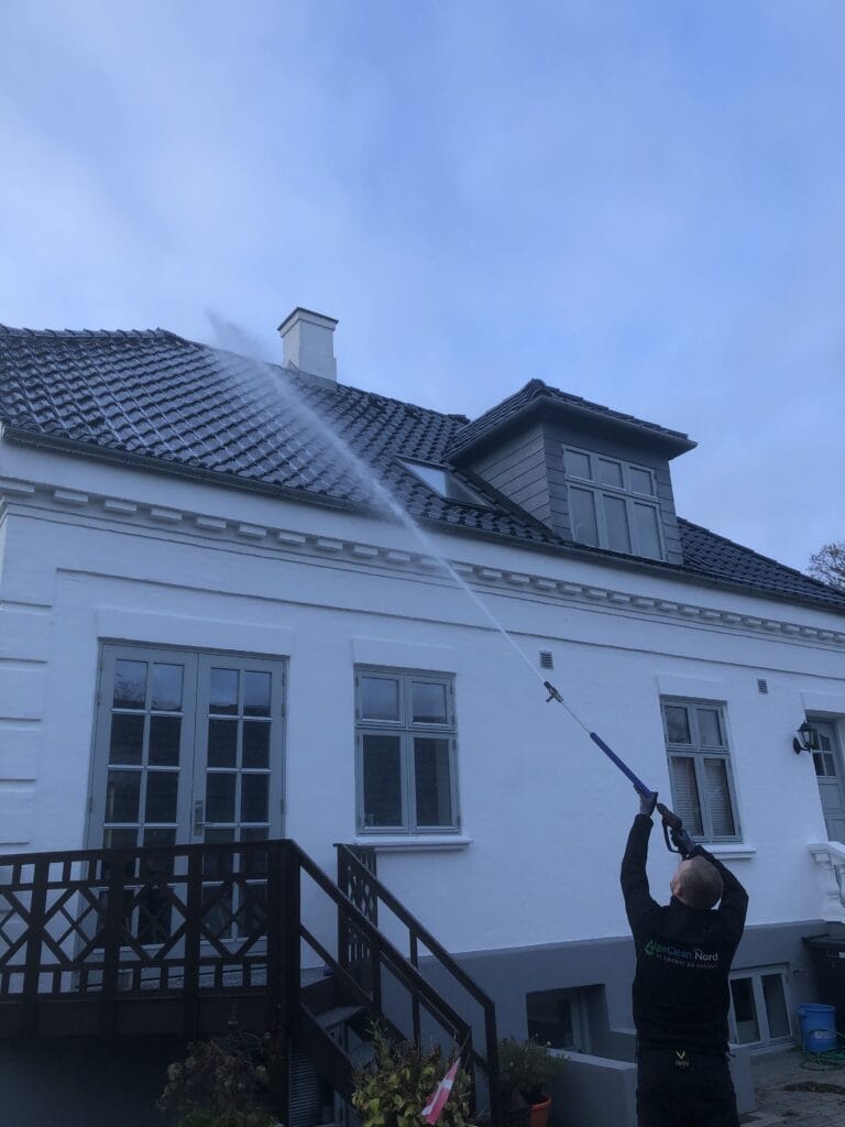 Mand rengør husets tag med højtryksrenser