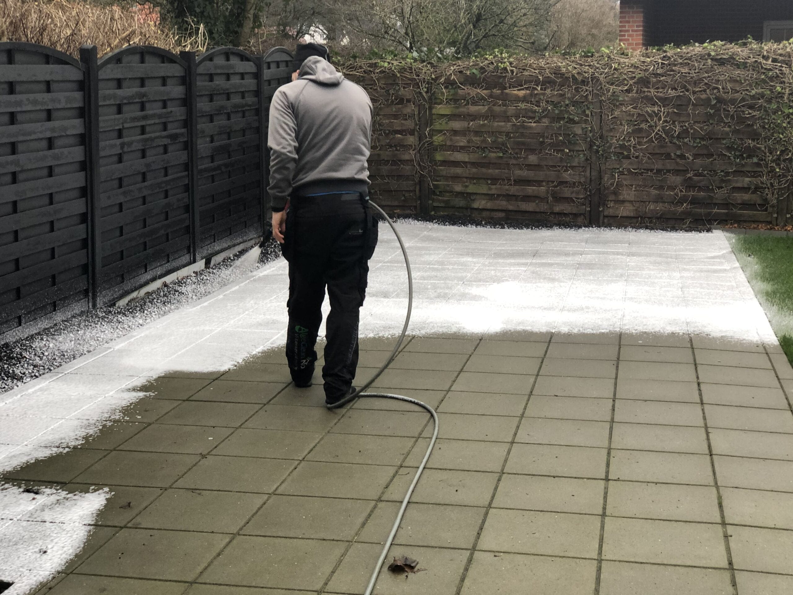 Person renser fliser med højtryksrenser i have