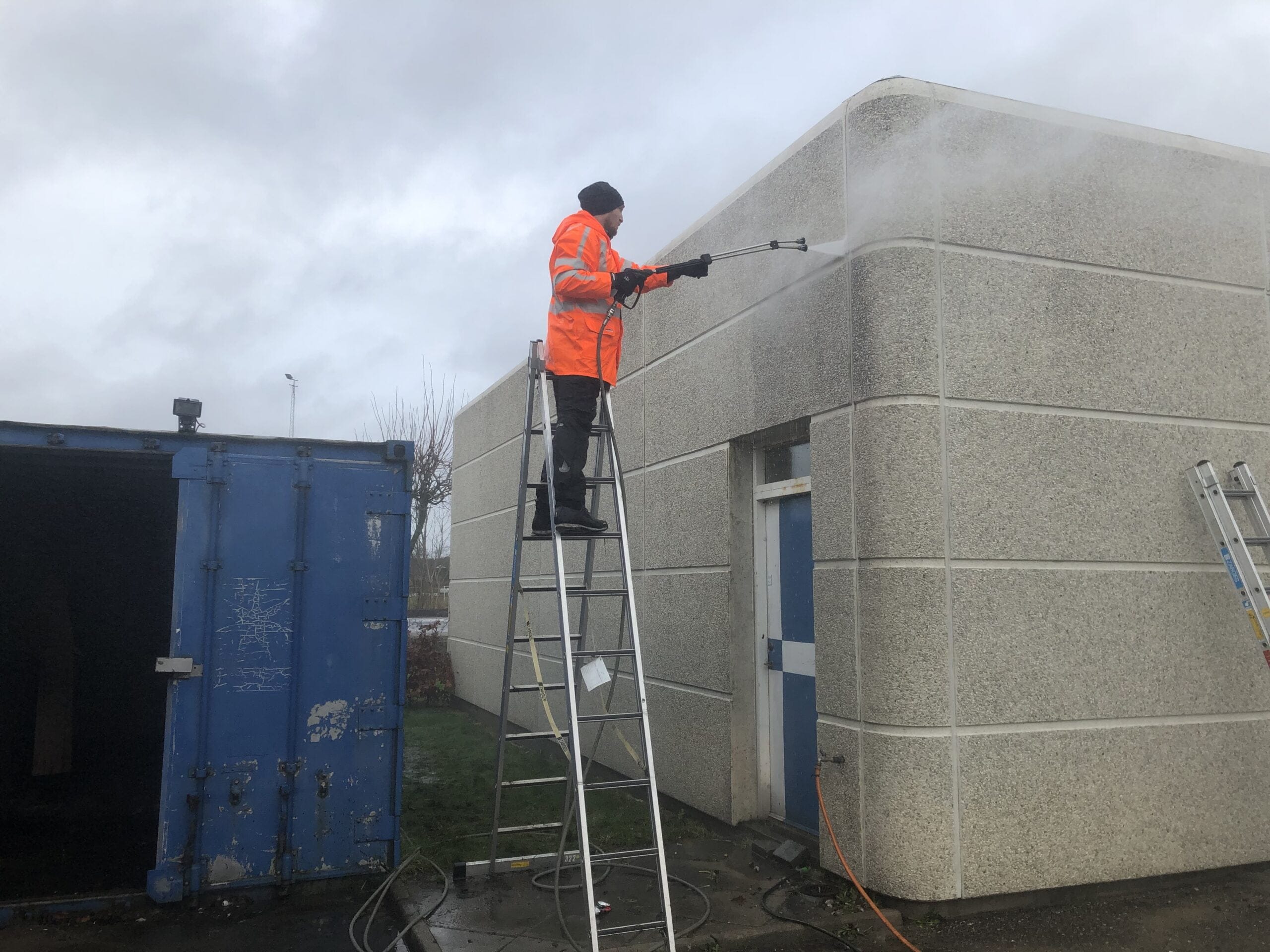 Person højtryksrenser bygning fra stige udendørs