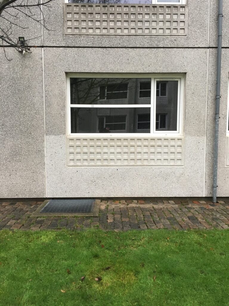 Vindue i grå betonbygning med græs foran